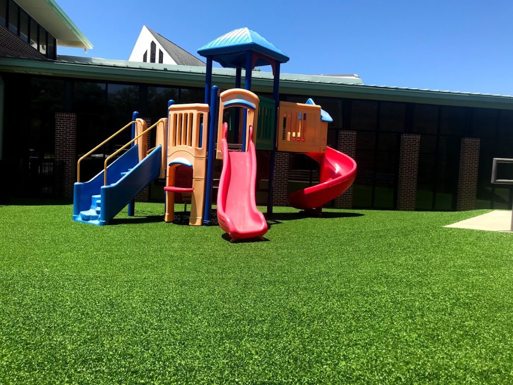 Soft green synthetic grass provides the perfect playground environment for children.