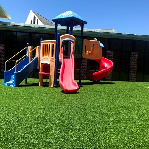 Soft green synthetic grass provides the perfect playground environment for children.