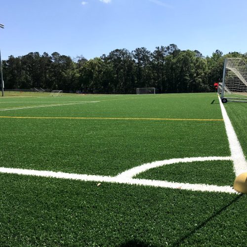 A beautiful synthetic grass soccer field with clean white lines.
